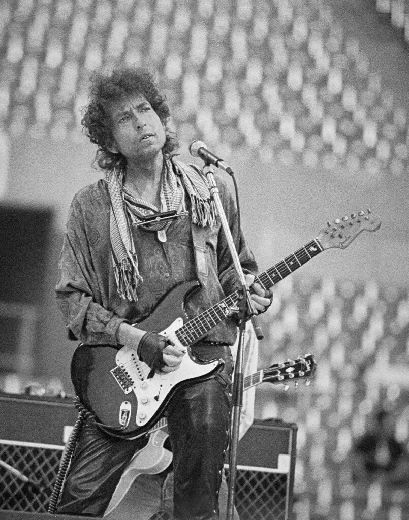 Bob Dylan performing on a black Fender Stratocaster at Rich Stadium, Buffalo NY, July 4, 1986 - concert photography by Chuck Spang