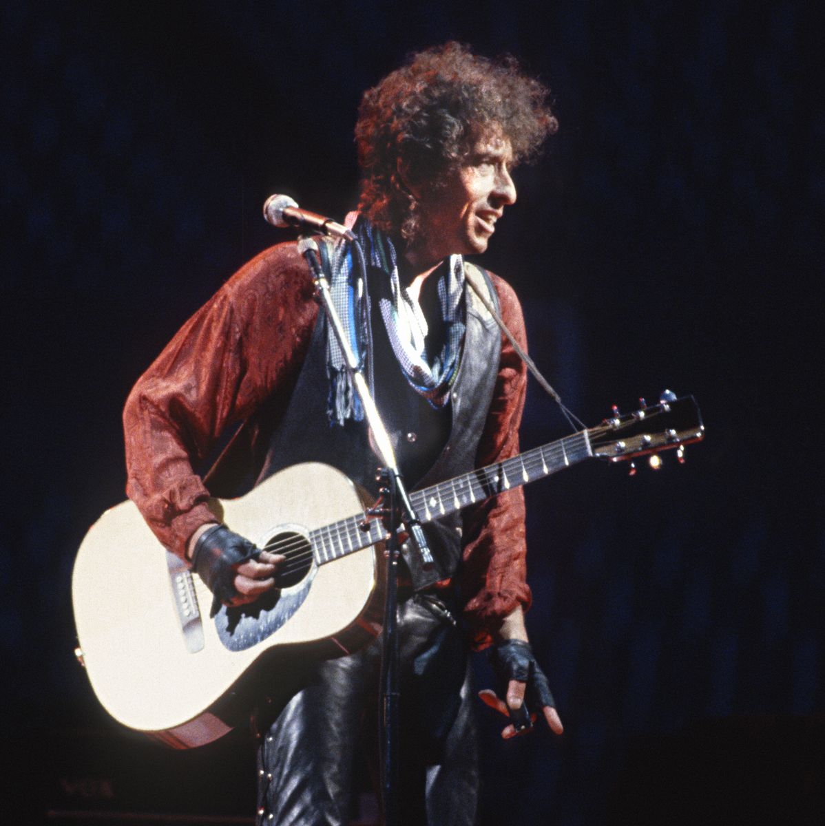 Bob Dylan performing on acoustic guitar at Rich Stadium, Buffalo NY, 1986 True Confessions Tour, color portrait - concert photography by Chuck Spang