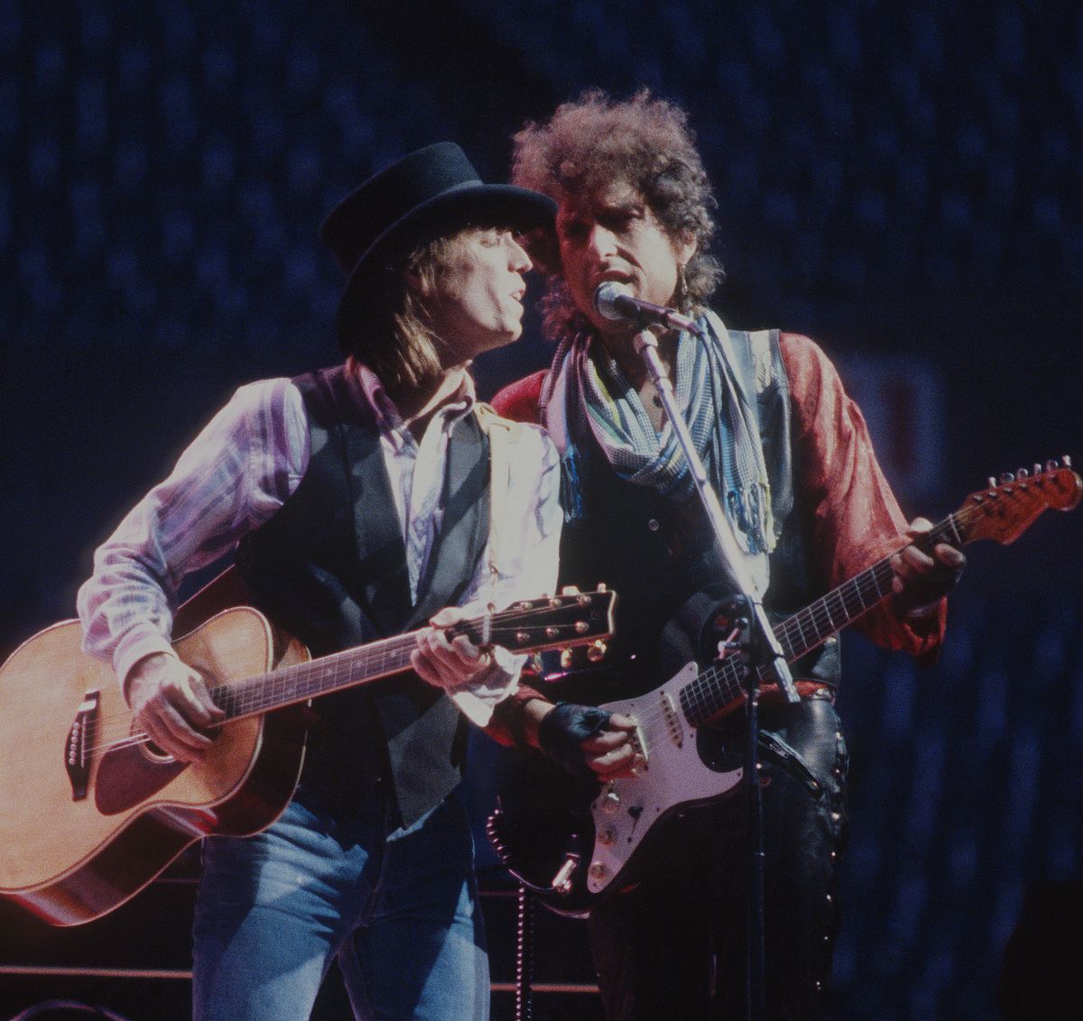 Bob Dylan and Tom Petty sharing a microphone at Rich Stadium, Buffalo NY, 1986 True Confessions Tour, Petty on acoustic guitar and Dylan on a Fender Stratocaster - concert photography by Chuck Spang