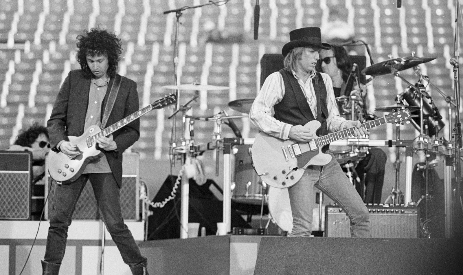 Tom Petty and Mike Campbell of the Heartbreakers on stage with drummer, Rich Stadium, Buffalo NY, 1986 True Confessions Tour, Campbell playing a Gibson Les Paul-style guitar - concert photography by Chuck Spang