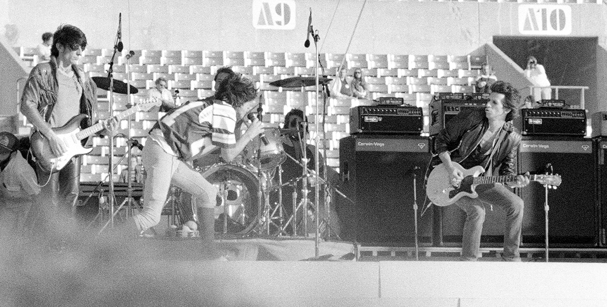 Mick Jagger charging across the stage between Ronnie Wood and Keith Richards, Rolling Stones at Rich Stadium, Buffalo NY, 1981 - concert photography by Chuck Spang